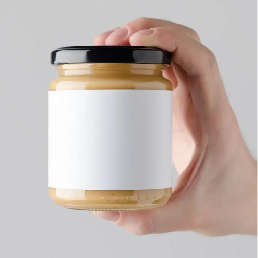 Unbranded glass jar of nut spread with a blank white label